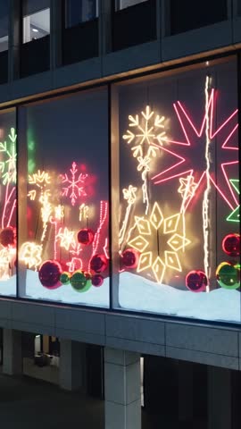 Vertical video panning across neon snowflakes and reflective baubles on office windows