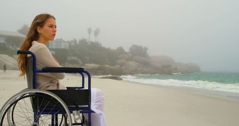 Contemplative Woman in Wheelchair on Misty Beach