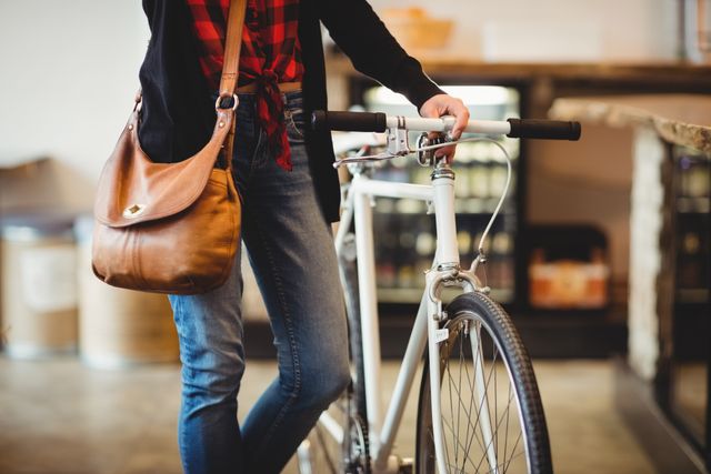 Mid section of woman standing along with bicycle at office cafeteria