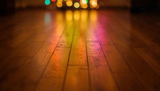 Warm hardwood floor reflecting colorful bokeh lights with visible wood grain and glow