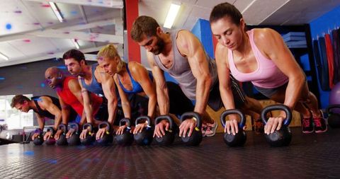 Group kettlebell plank push-ups building core strength during intense gym training session