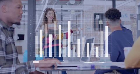 Presenting team leader pointing at glass whiteboard with bar chart overlay in creative office