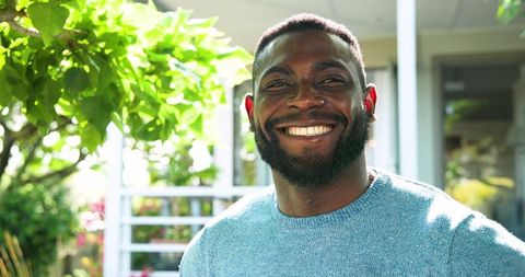 Smiling Young Man on Porch Surrounded by Greenery