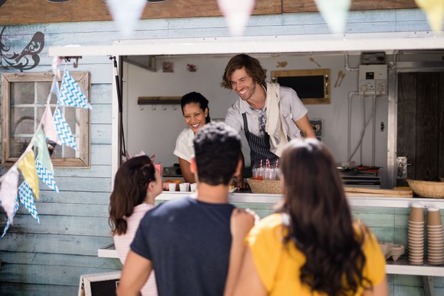 Smiling waiter giving order to customer at counter in food truck van