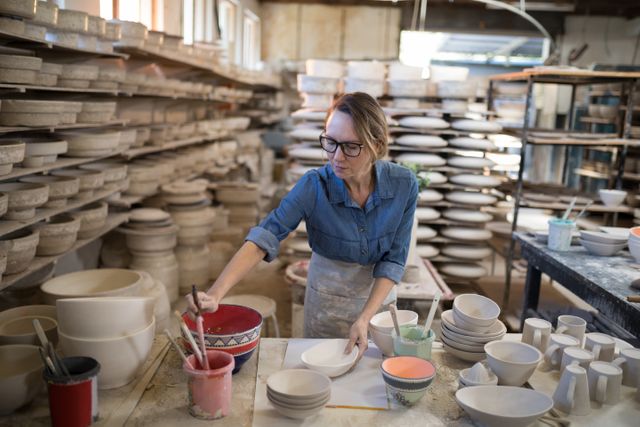 Female potter painting bowl in pottery workshop