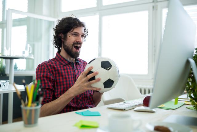 Male graphic designer cheering while watching football match in office