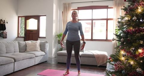 Senior Woman Engaging in Christmas Fitness by Decorated Living Room Tree
