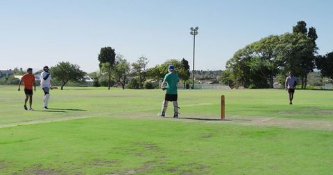 Casual weekend cricket match with batter playing at crease on sunny park field, players in action