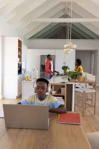 African American family managing remote learning and home life in bright modern kitchen