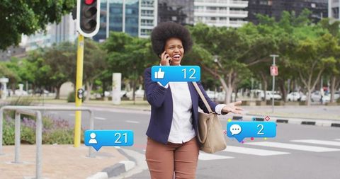 Smiling midadult businesswoman walking, talking on phone with social media notifications