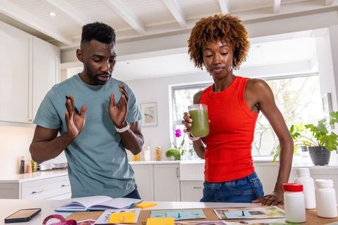 African american couple planning future at kitchen island, woman holding green smoothie