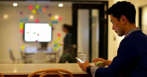 Asian Businessman Using Smartphone in Modern Office