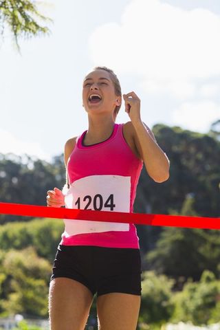 Female runner celebrating cross-country race victory at finish line