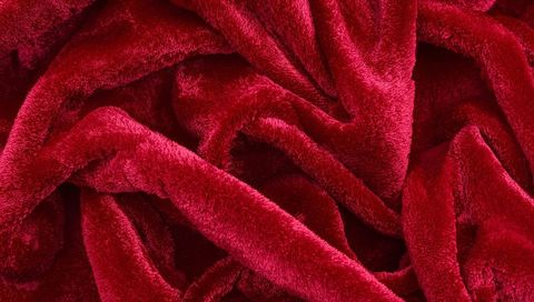 Crimson plush velvet blanket texture closeup showing soft pile and luxurious folds
