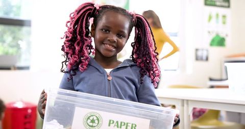 Young Girl Recycling Paper in Classroom Environment