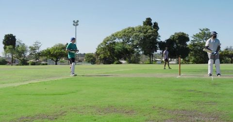 Cricket match batsman batting and wicketkeeper fielding on sunlit park pitch