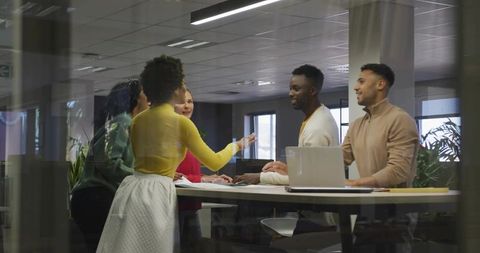 Leading discussion at standing table in modern office team meeting colleagues collaborating