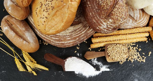 An assortment of freshly baked bread including seeded loaves, rolls, and breadsticks on a black background. Display of flour and grains adds to the authentic bakery feel. Useful for illustrating topics on homemade bread, organic ingredients, artisanal bakeries, food recipes, and culinary arts.