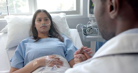Male Doctor Comforts Female Patient in Hospital Bed