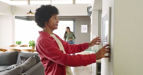 Couple decorating modern open-plan living room with framed picture