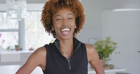 African american woman laughing with hands on hips in bright minimalist kitchen interior