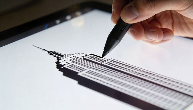 Architect sketching empire state building silhouette on tablet with digital stylus