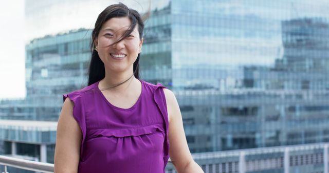 Smiling Businesswoman in Purple Blouse Outdoors with Glass Building in Background - Download Free Stock Images Pikwizard.com