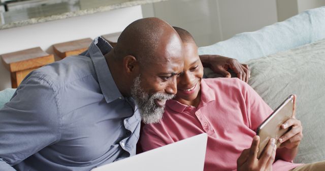 Image of happy african american father and son using tablet together. Family, spending quality time together at home.