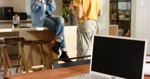 African american couple chatting casually in modern home kitchen with open laptop
