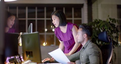 Diverse professionals collaborating late night in modern office
