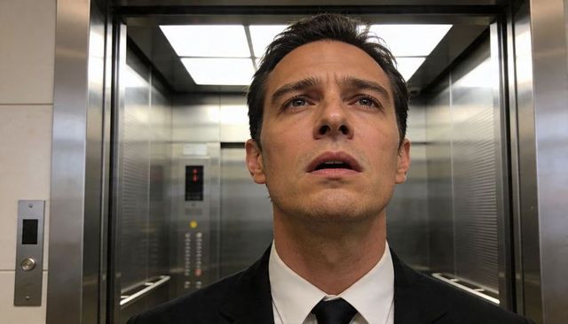 Businessman Looking Up in Elevator Interior Reflective Metal Corporate Tension