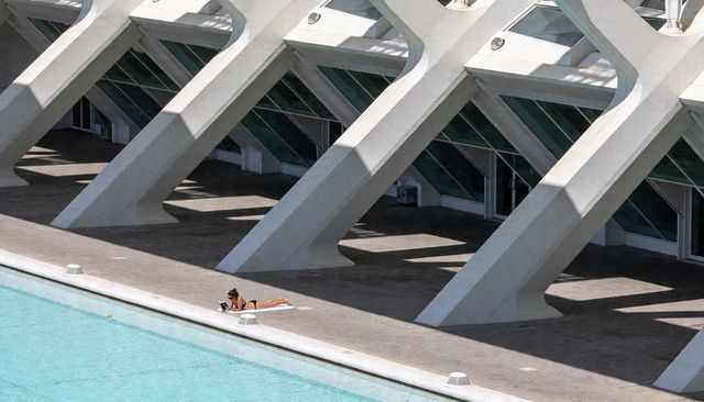 Solitary sunbather reading beside modern concrete architecture and turquoise pool