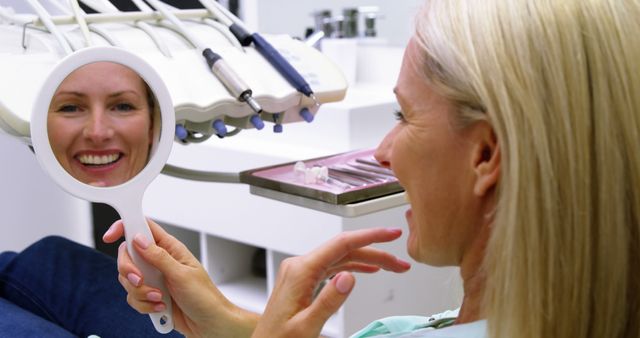 Woman at Dental Office Examining Teeth in Hand Mirror - Download Free Stock Images Pikwizard.com