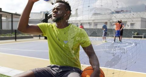 Urban basketball player hydrating on outdoor court with digital globe and data overlay