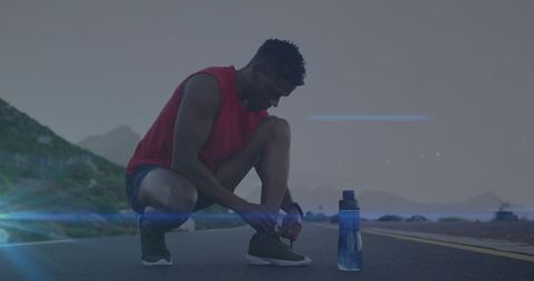 Fit Man Preparing for Run Tying Shoe Laces with Water Bottle