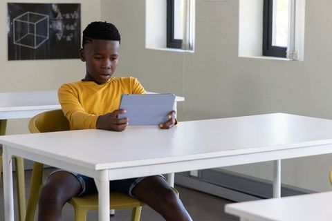 African american preteen using tablet in classroom studying geometry and digital learning