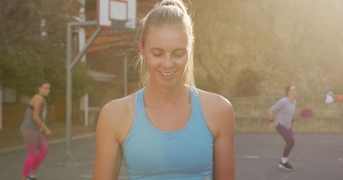 Smiling female basketball player on outdoor court at sunset