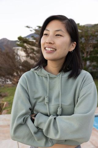 Confident Young Woman Standing by Backyard Pool in Casual Hoodie