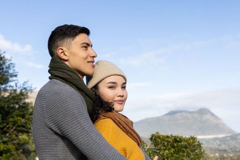 Young couple embracing on mountain overlook, enjoying serene scenic view