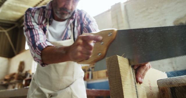 Carpenter Cutting Wood with Handsaw in Workshop - Download Free Stock Images Pikwizard.com