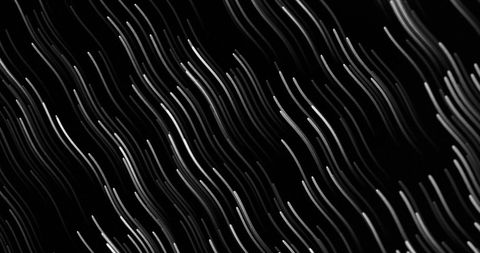 Dynamic glowing light trails in motion on black background