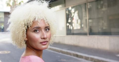 Thoughtful Young Woman with Curly Blonde Hair in Urban Setting - Download Free Stock Images Pikwizard.com