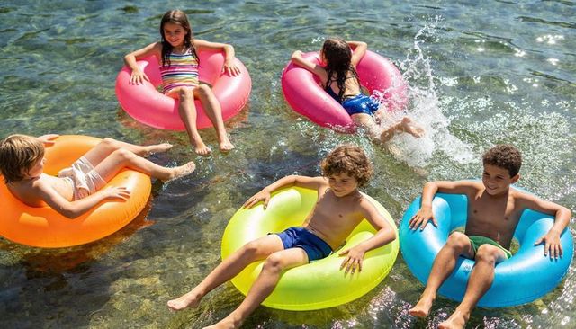Kids floating on colorful inflatable rings in clear shallow water enjoying summer fun