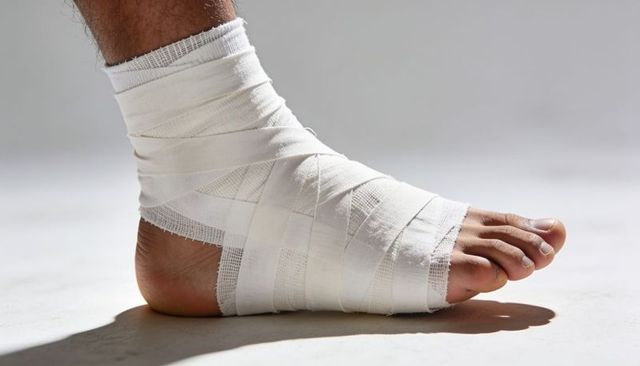 Resting bandaged foot with ankle wrap gauze and adhesive tape close-up medical care