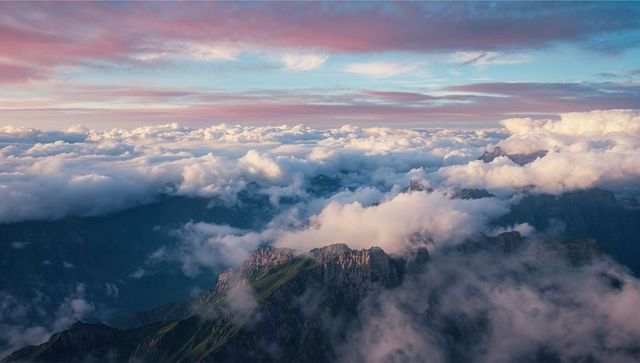 Aerial View of Mountain Ridge Above Clouds During Sunrise