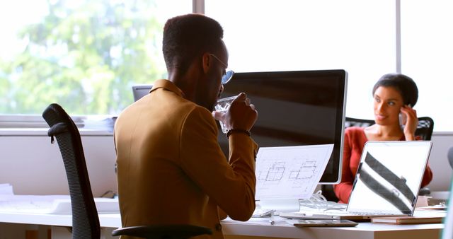 Architect Drinking Water while Reviewing Blueprints in Modern Office - Download Free Stock Images Pikwizard.com