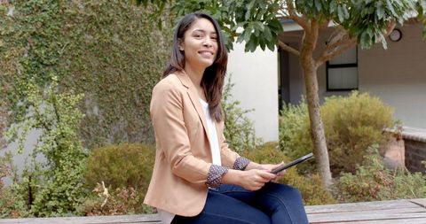 Confident Young Woman with Tablet in Peaceful Outdoor College Campus