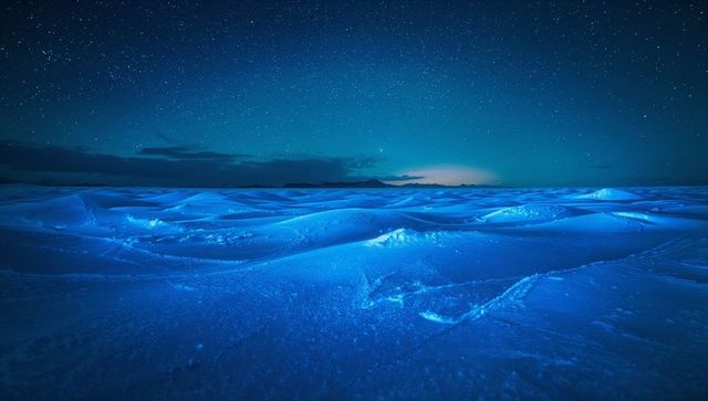 Moonlit blue snow dunes stretching across frozen arctic plain under starry sky