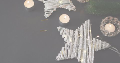 Festive silver stars and candlelight on dark surface