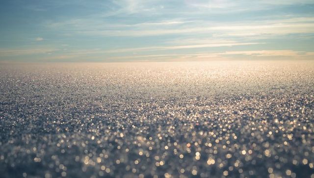 Sparkling sunlit sea horizon with pastel sky and bokeh reflections, minimalist coastal tranquil mood